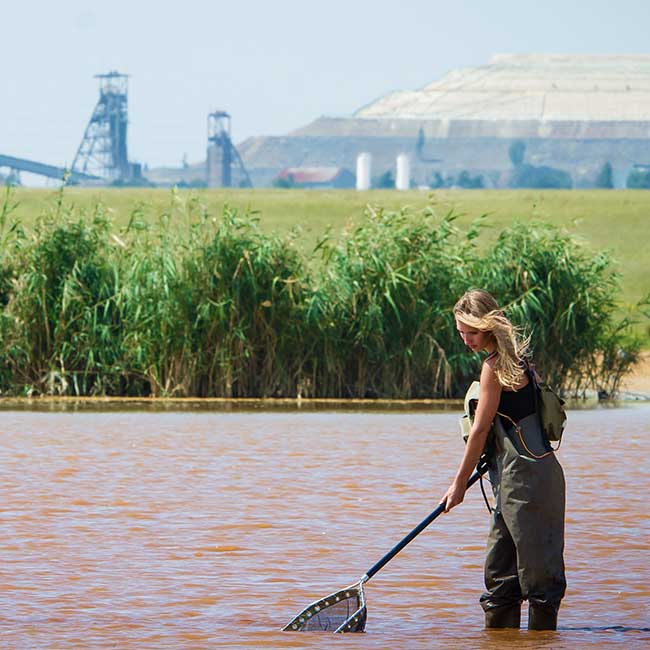 person in water next to a mining operation